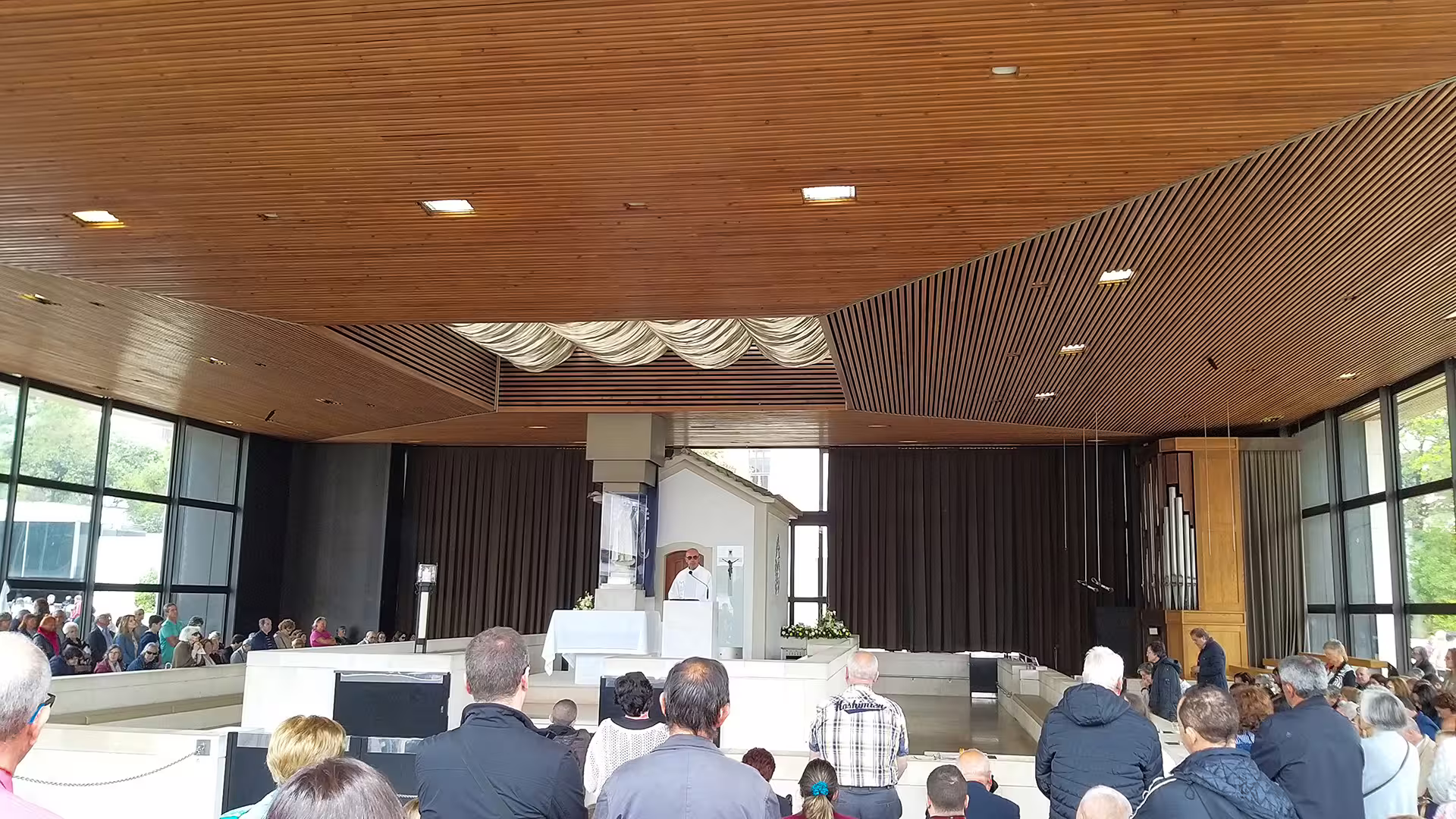 Interior view of a serene chapel with visitors gathered for a service, part of a customized private tour from Porto to Lisbon.