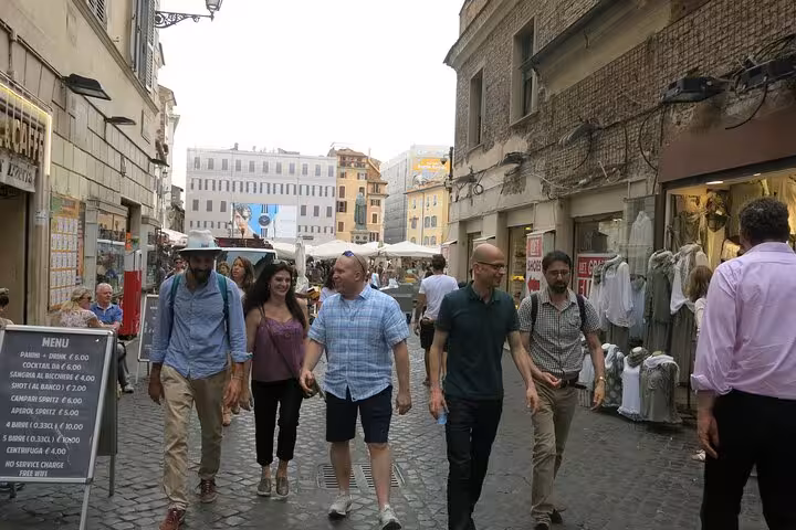 Group of tourists exploring a lively Roman street market on a private vegetarian food tour.