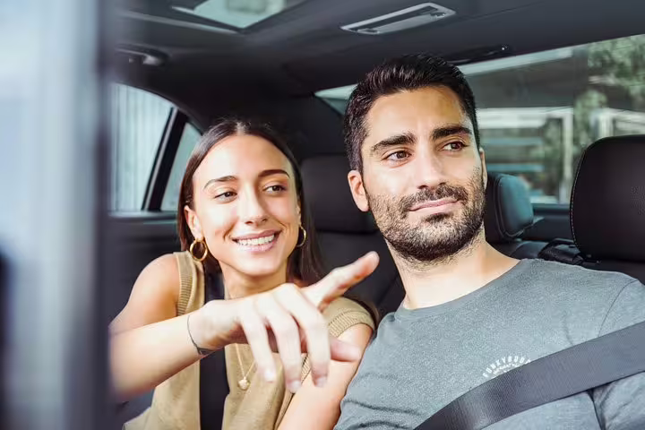 Couple in private car with driver, pointing out sights on a Rome half-day private sightseeing tour transfer