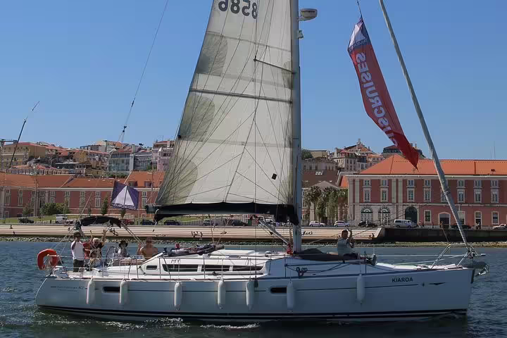 Private sailboat cruise along Lisbon's scenic waterfront, showcasing historic architecture and vibrant city life.