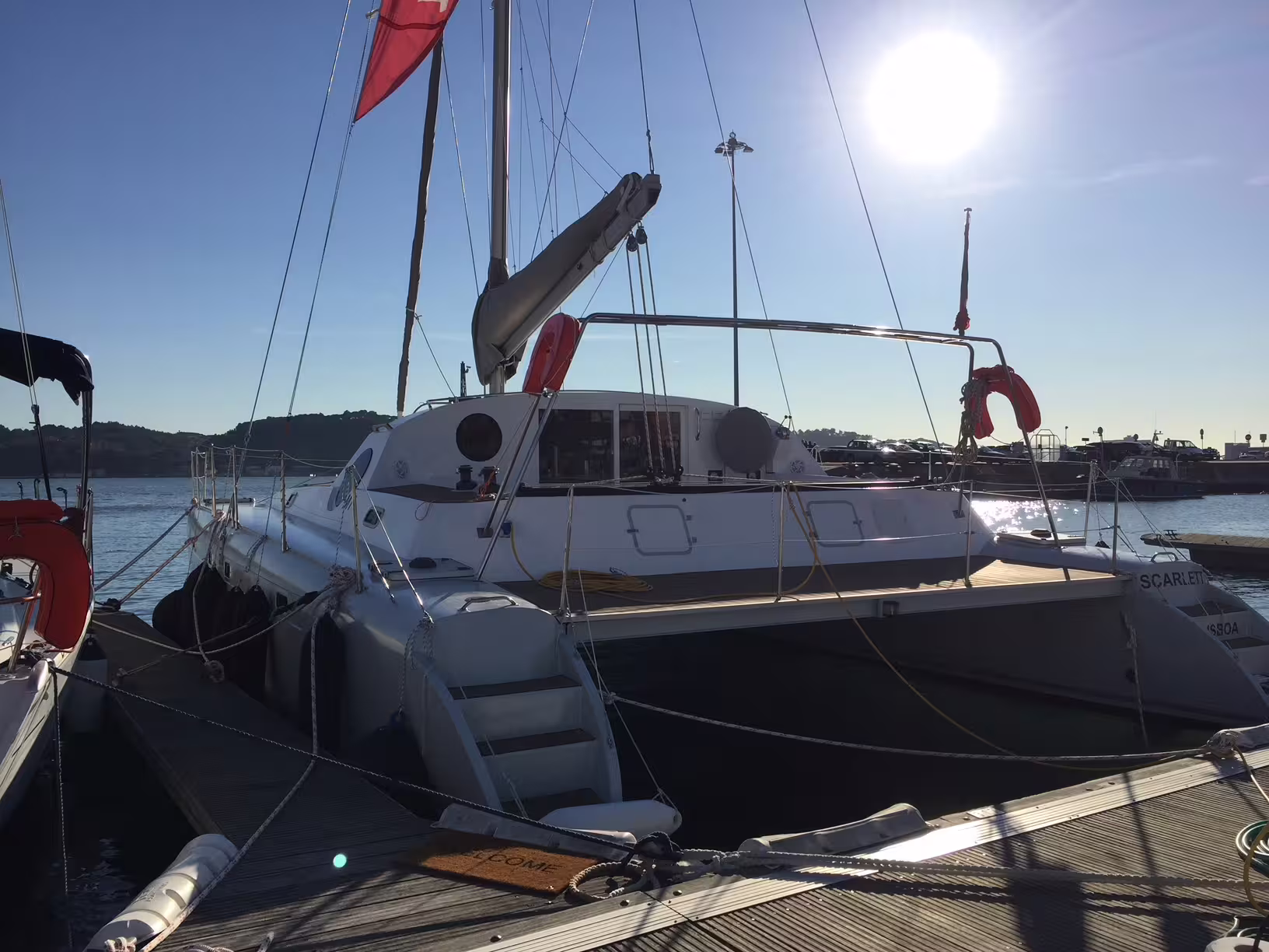 A private sailing catamaran 'Scarlett' docked under a bright sun, ready for a 2-hour tour, accommodating up to 16 people.