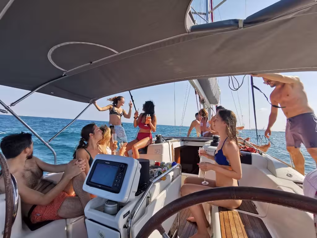 Group enjoying a private 3-hour sailing experience on a sunny day in Barcelona, relaxing and socializing on a sailboat.
