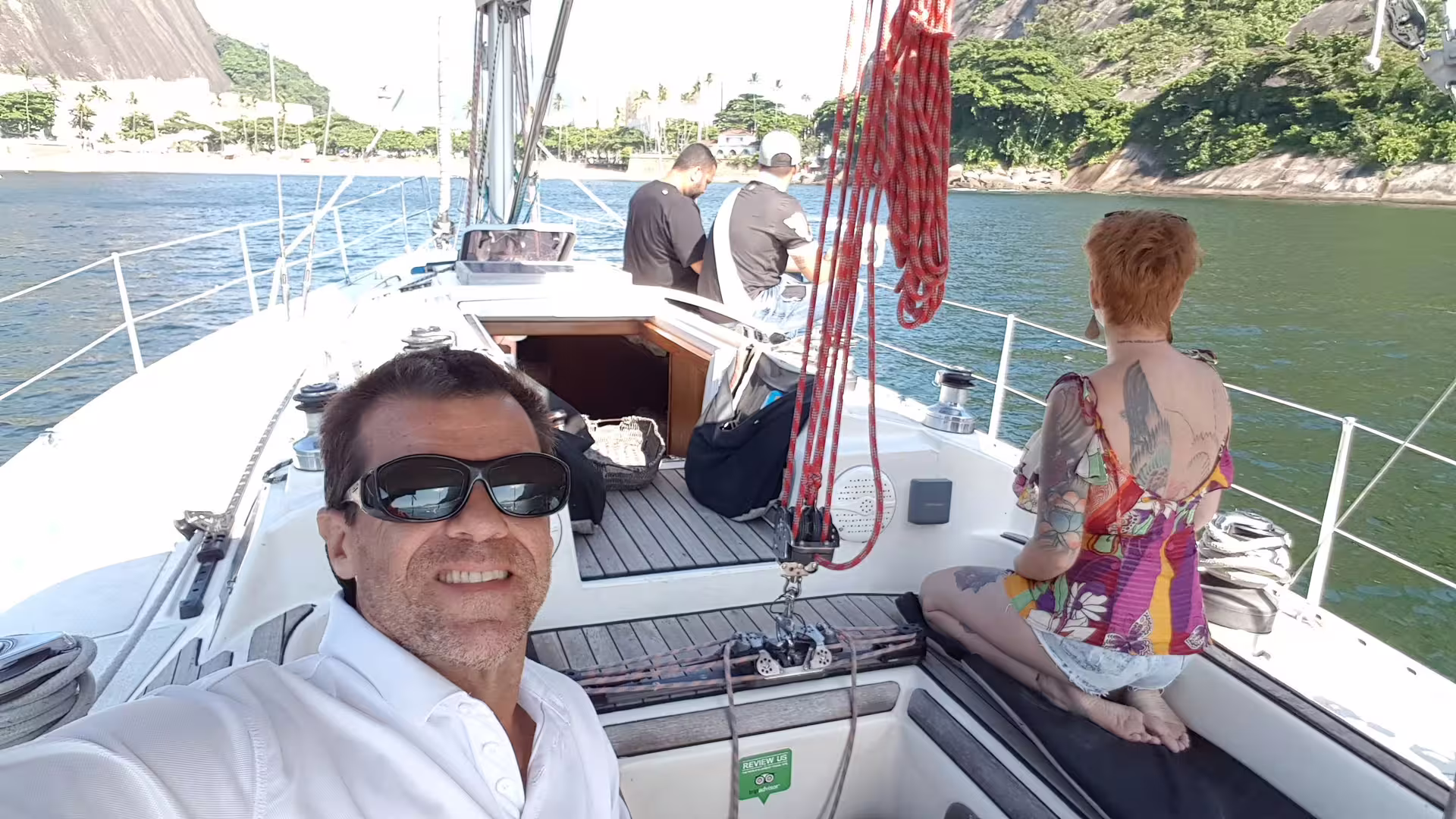 Smiling man on a private sailing tour with friends enjoying the sunny coastal views and vibrant scenery.
