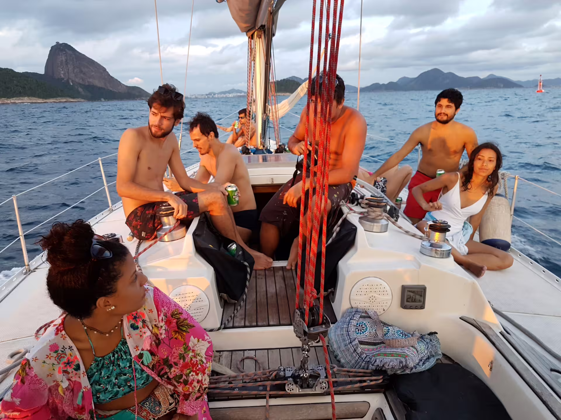 Group relaxing on a private sailing tour, soaking up the sun and ocean views with a picturesque mountain backdrop.