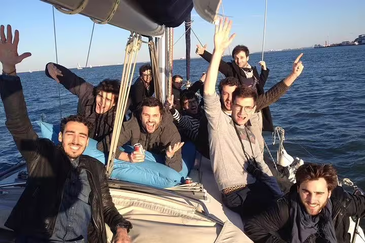 Group of friends joyfully enjoying a private sailing tour on Lisbon's waters with sunny weather and smiles.