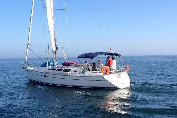 Group enjoying a sunny day on a sailboat during a 4-hour private sailing tour to Oeiras beach.