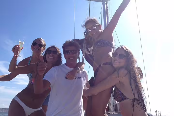 Happy group celebrating on a sailboat during a sunny 4-hour private sailing trip to Oeiras beach.