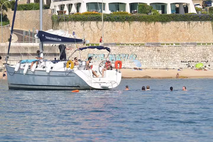 Group enjoying a private sailing trip with swimming near Oeiras beach, surrounded by scenic coastal views.