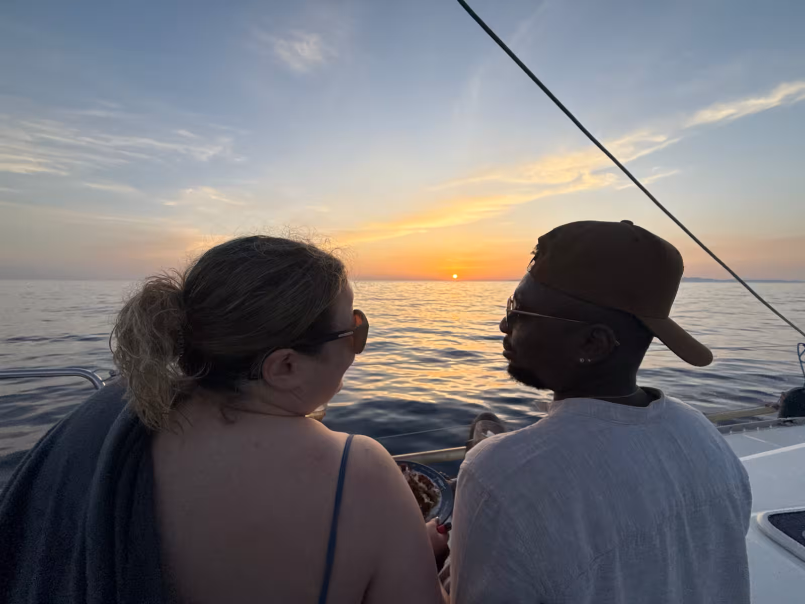 Couple watching the Santorini sunset from a private sailing catamaran cruise on the Aegean Sea
