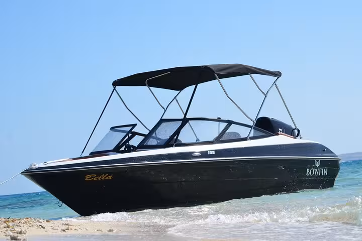 Private speedboat on Red Sea shore in Hurghada for Hula Hula Island snorkeling trip with shaded canopy