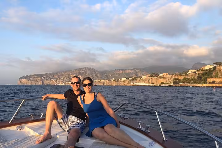 Couple enjoying a private sunset boat tour off the Sorrento coast with scenic coastal views.