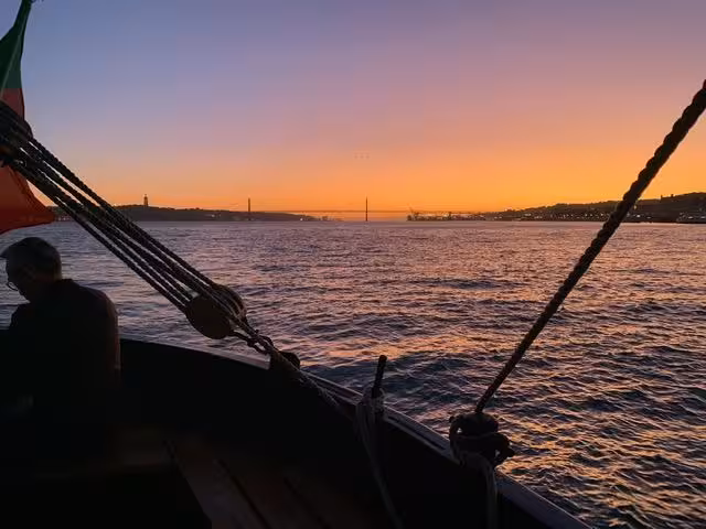 Private sunset Lisbon boat tour on the Tagus River with golden sky views toward the 25 de Abril Bridge