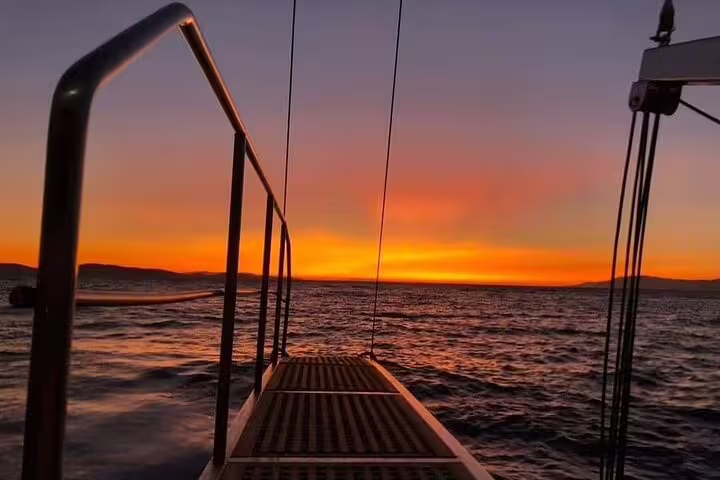Experience a breathtaking private sunset on a motorboat in Milos, Greece, with vibrant skies reflecting over serene waters.