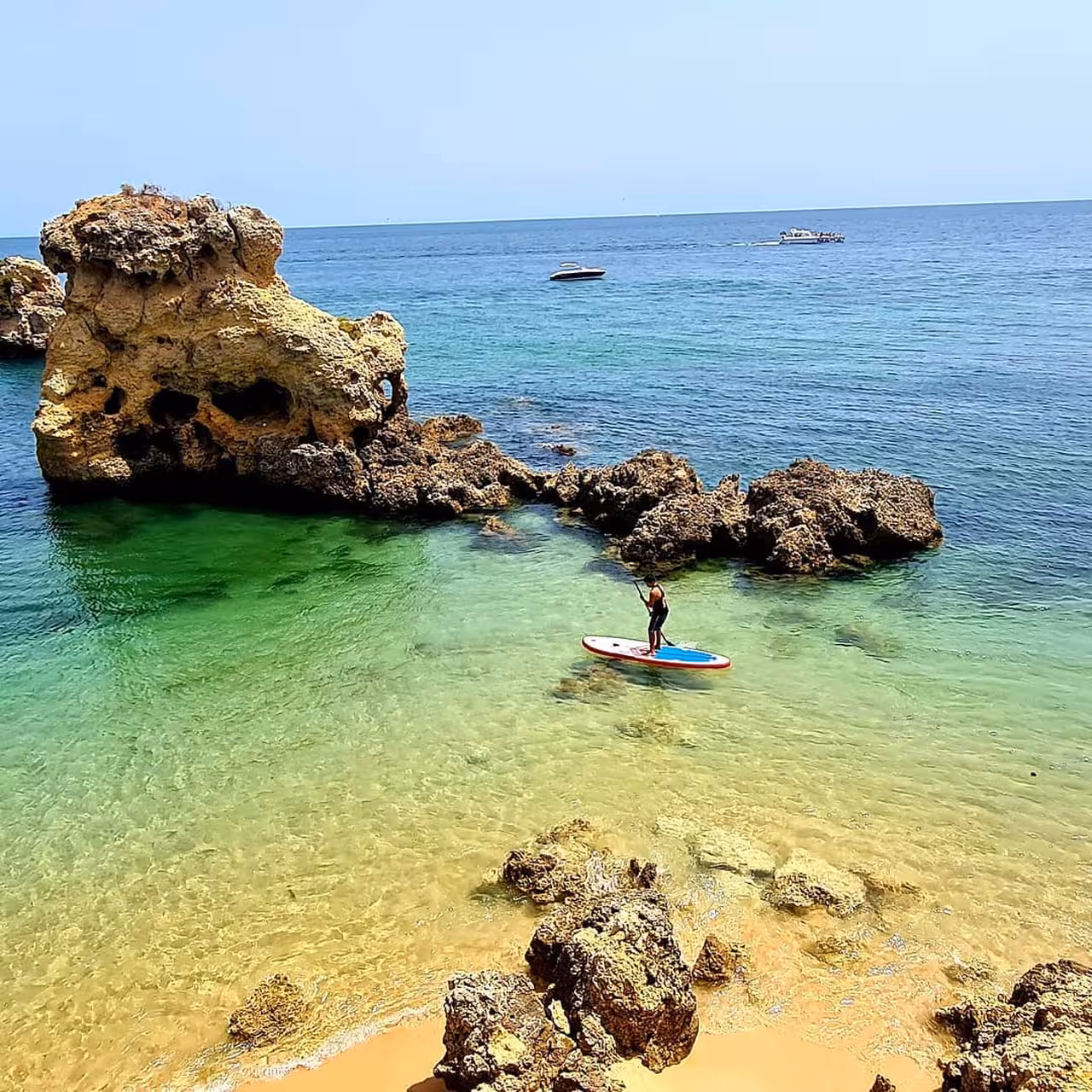 Solo paddleboarder exploring crystal-clear turquoise waters near Albufeira sea caves on a private SUP tour