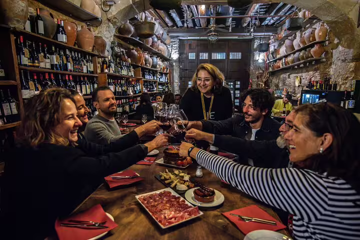 Cheers and laughter during a private tapas and wine walking tour in a rustic Spanish wine cellar.