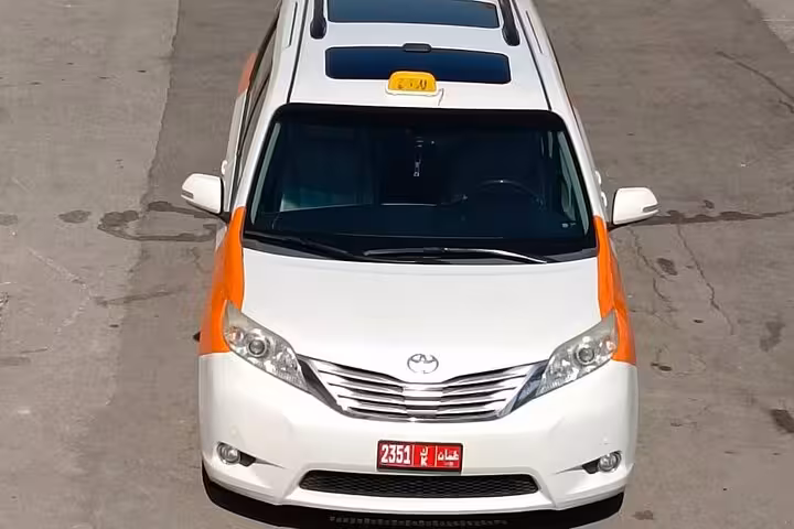 Modern white taxi minivan used for private departure transfers from Shangri-La Muscat resort to Muscat International Airport