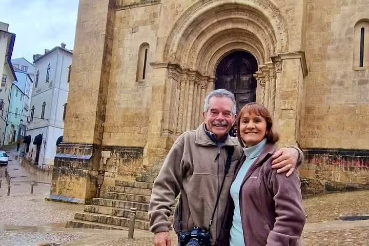 Couple enjoying a private full-day tour from Lisbon, posing in front of the historic architecture in Tomar, Portugal.
