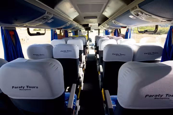 Interior view of a sleek tour bus offering private transportation from Búzios to Rio de Janeiro with ample seating.