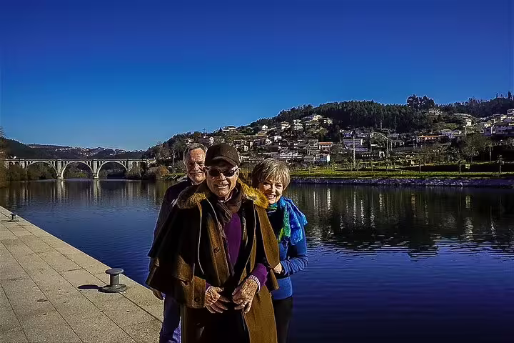 Private tour guests by the Douro River in Porto, Portugal, with bridge and hillside views on a 2-day trip