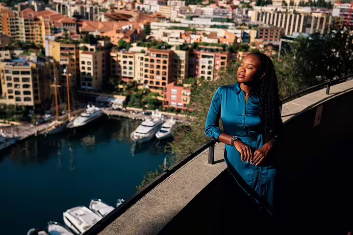 Woman in blue dress enjoys scenic view of Nice's vibrant harbor and city from a high vantage point during a private tour.