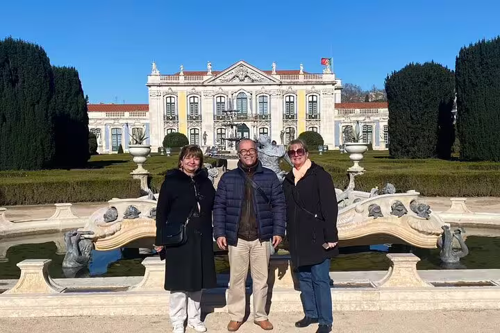 Three tourists enjoying a sunny day at a historic palace garden in Sintra during a private tour from Lisbon.