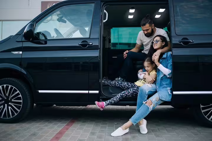 Happy family enjoying a moment by their luxury van during a private transfer from AltaBadia to Venice.