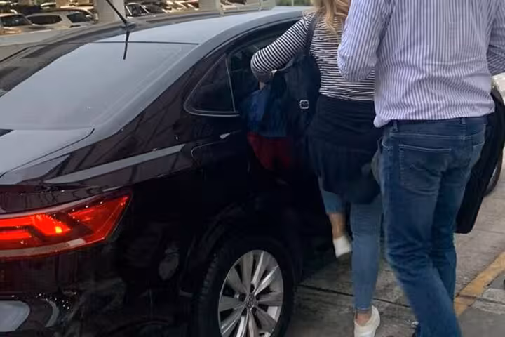 Passengers entering a sleek black car for private transfer service from Guarulhos Airport to São Paulo accommodations.