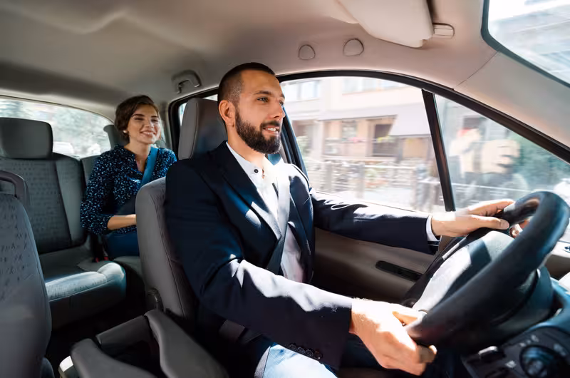 Friendly driver and passenger in a private transfer from Lisbon Airport to hotel, offering comfort and convenience.