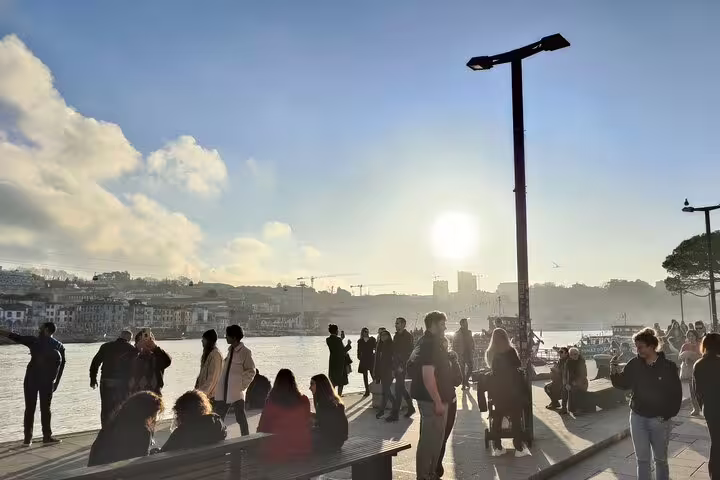 People enjoying a scenic riverside sunset in Porto, perfect for a private transfer experience from Lisbon with sightseeing stops.