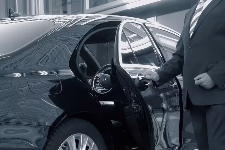 Professional chauffeur opening luxury sedan door for private transfer from Marsa Alam to Hurghada