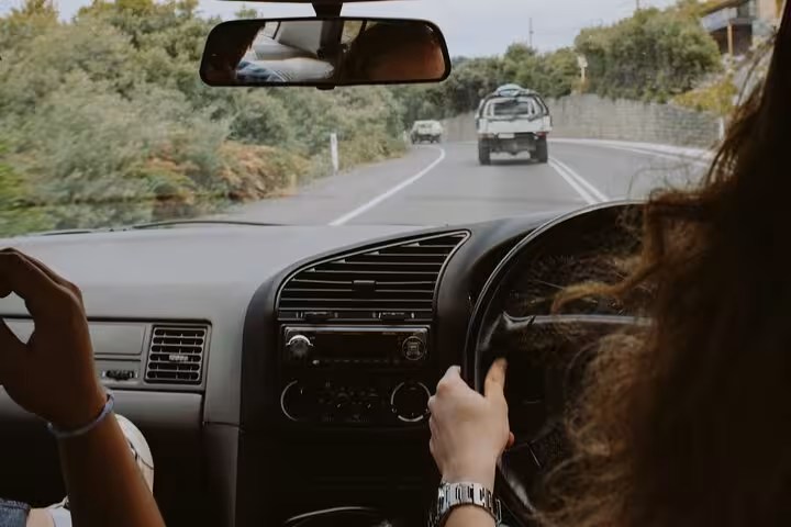 View from inside private car driving from Muscat to Dubai on scenic highway, showing relaxed passengers and safe driver