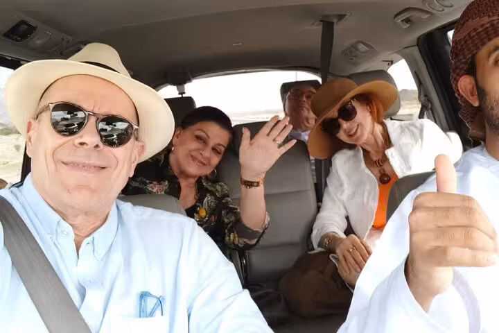 Happy tourists enjoy a comfortable private transfer in an air-conditioned car from Muscat to Nizwa with local driver