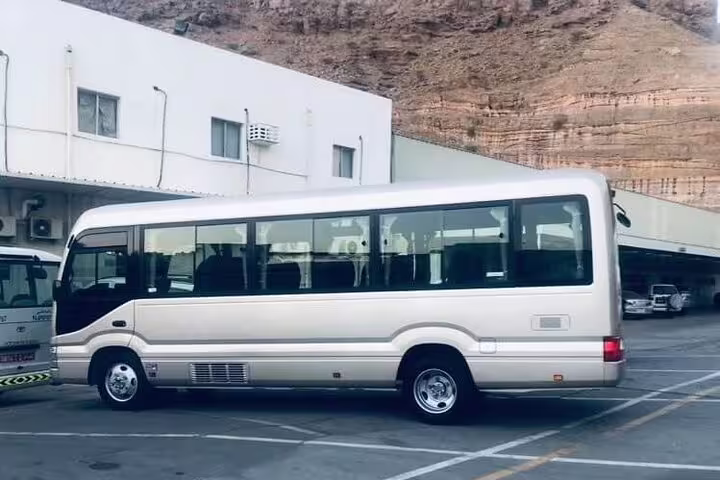 Comfortable tour bus ready for private transfers from Muscat to Wadi Shab, offering group travel convenience.