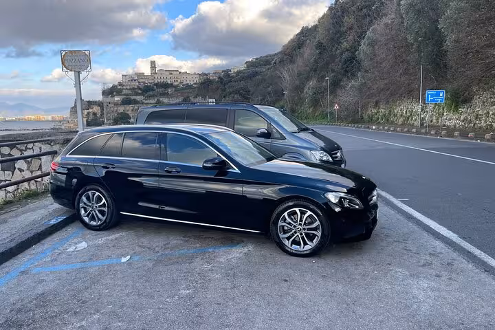 Elegant black Mercedes cars parked on scenic route from Naples to Positano, ideal for private transfers.