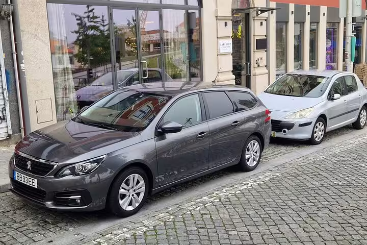 Two cars parked along a city street, perfect for comfortable private transfers between Porto and Lisbon.