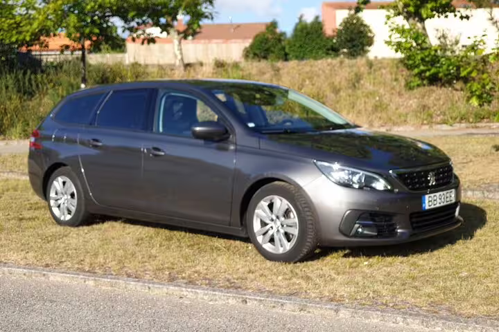 Sleek gray car ready for private transfers between Porto and Lisbon, parked on a grassy roadside.