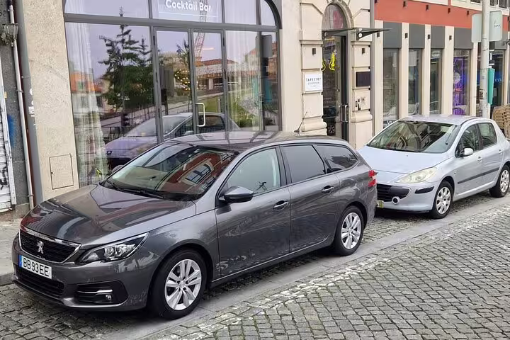 Stylish grey car parked near a cocktail bar in Porto, ideal for private transfers.