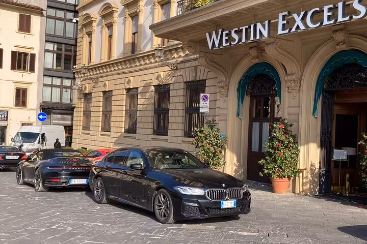 Elegant BMW car parked outside a historic hotel in Rome, ideal for a private airport transfer to Fiumicino.