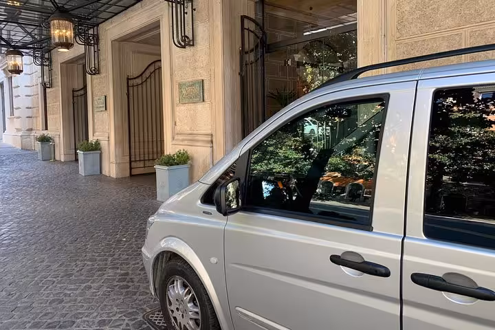 Silver van parked outside a hotel, ready for private transfer service from Naples to Sorrento for travelers.