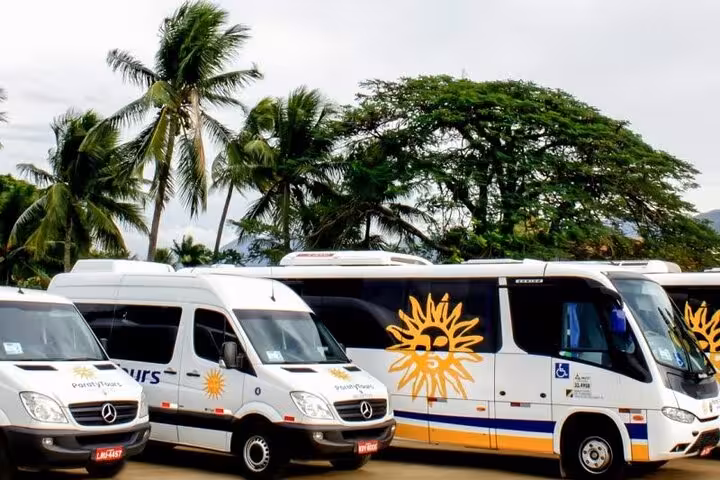 Comfortable private transport vans parked amidst palm trees for Rio de Janeiro to Paraty scenic journey.