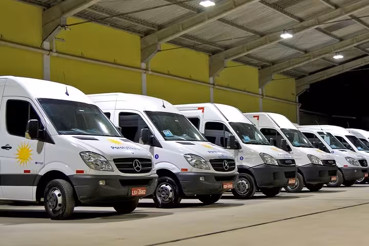 Fleet of modern transport vans ready for private transfers from Rio de Janeiro to Paraty under a sheltered area.