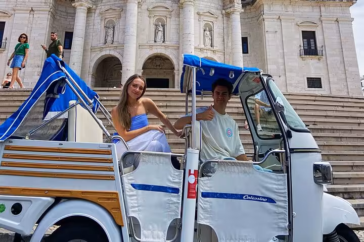 Private tuk tuk tour guests at Lisbon Cathedral steps, 2-hour historic Lisbon sightseeing by tuk tuk