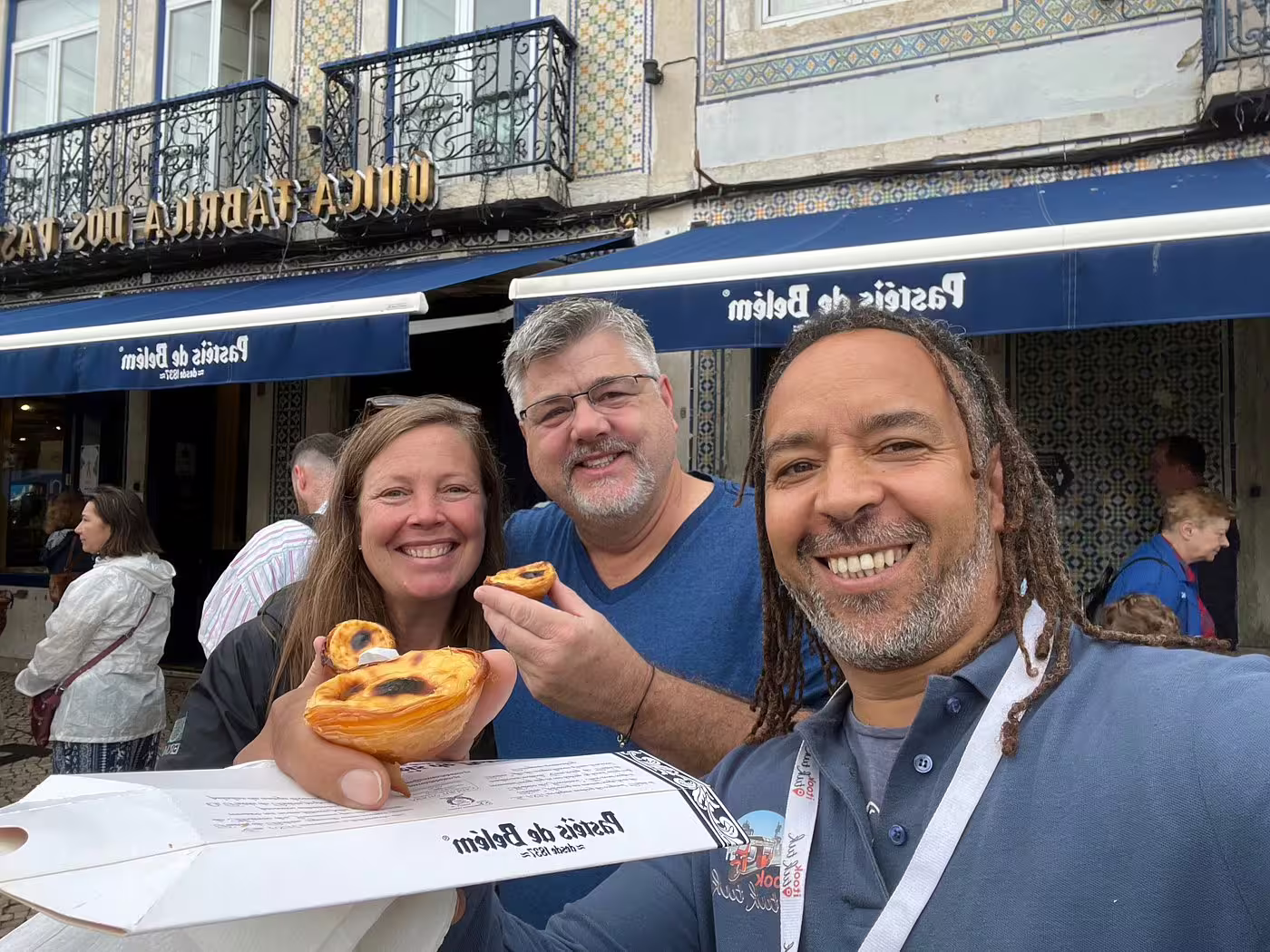 Tourists savoring traditional Pastéis de Belém pastries during a private tuk tuk tour in Lisbon.