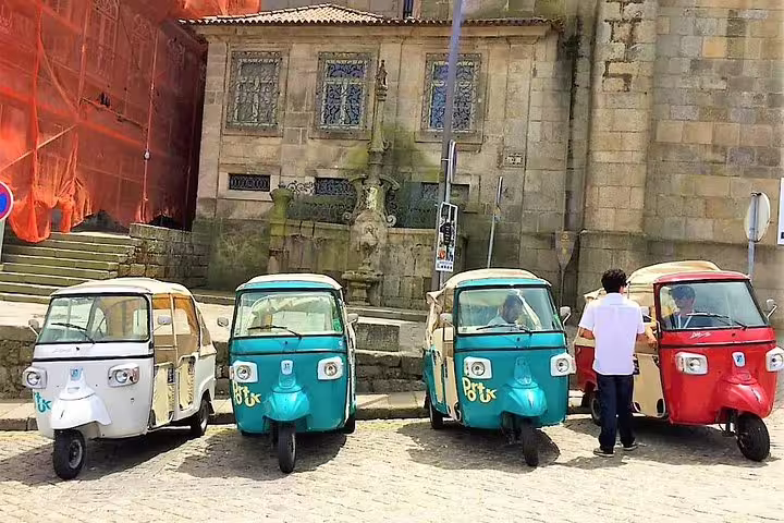 Colorful tuk-tuks parked in front of historic Porto architecture, perfect for a private half-day city tour adventure.