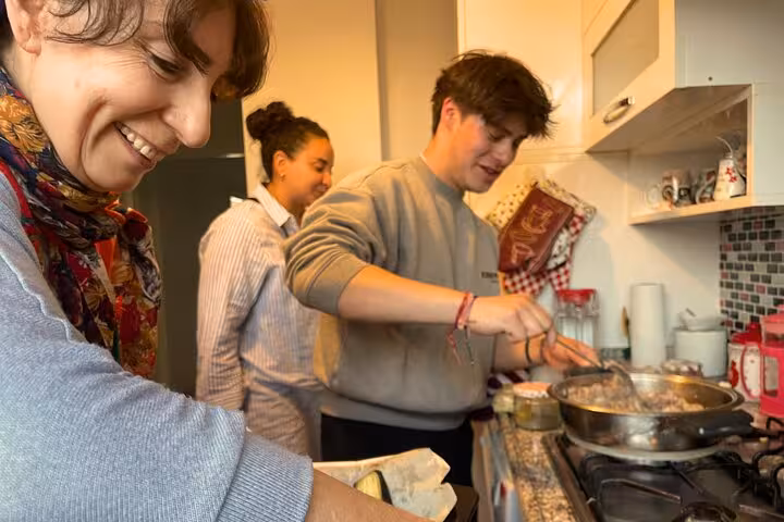 Guests cook with local Turkish moms in a home kitchen, stirring a pan during a private cuisine class