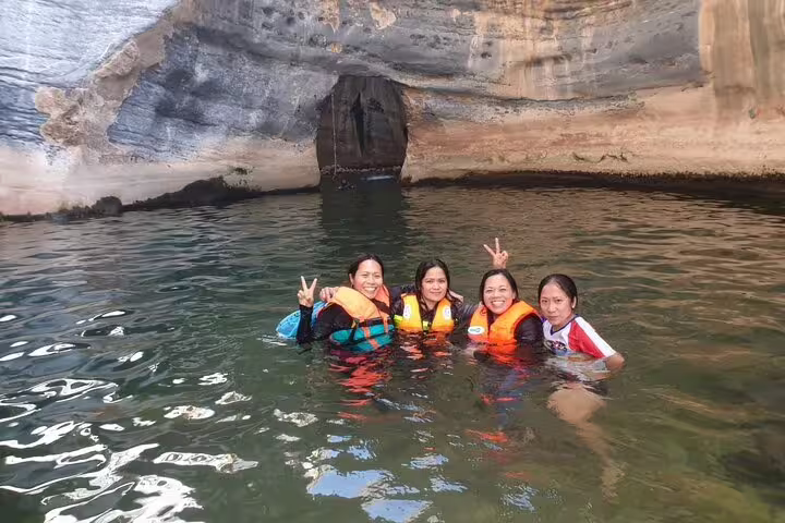 Group enjoying a refreshing swim in a serene cave pool during a private full-day Wadi Dham tour adventure.