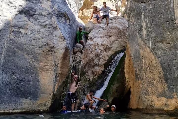 Group of adventurers exploring waterfall and rock formations on the Private Full Day Wadi Dham Tour in Oman.