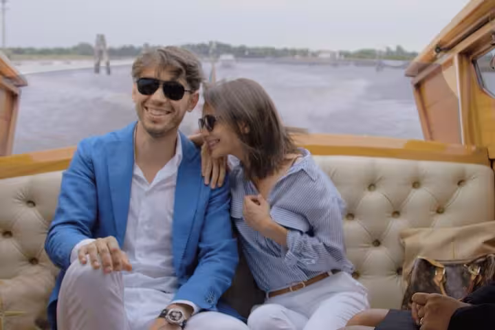 Couple enjoying a private water taxi from Venice Airport to Venice with scenic views of the lagoon.