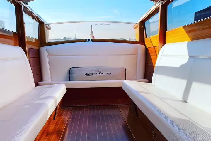 Luxurious interior of a private water taxi in Venice, featuring comfortable white seating and wooden accents.