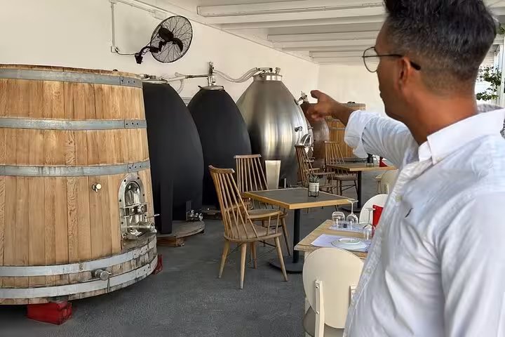 Private winery tour tasting room with oak barrel and steel tanks, ideal for Wine Museum tasting with snacks